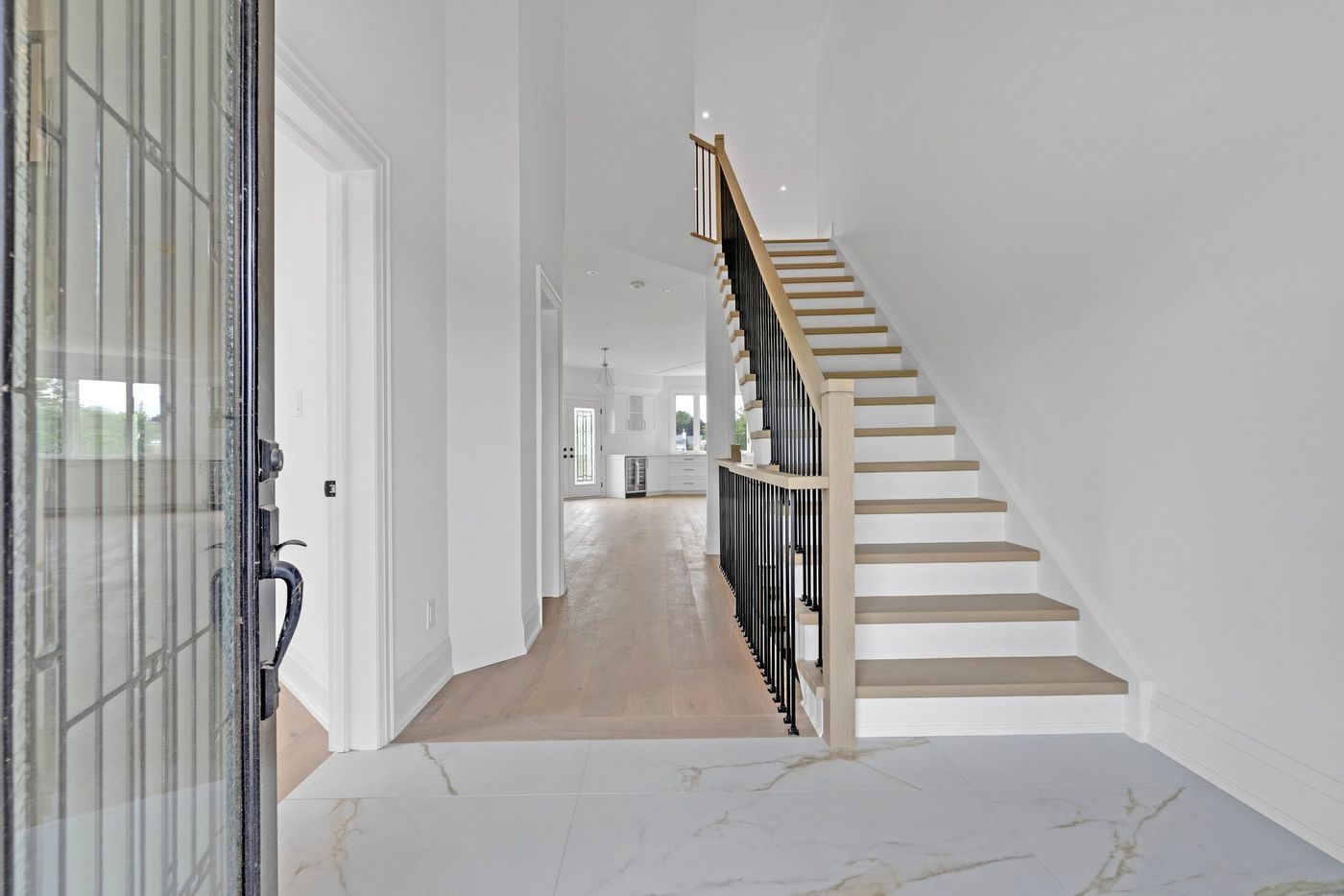 Foyer with oak staircase and view to the kitchen